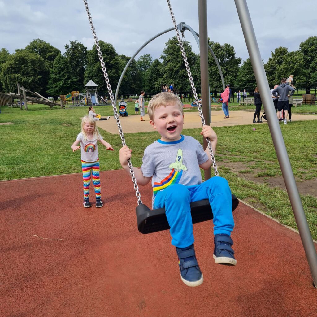 Summer holiday mode girl pushing boy on swing