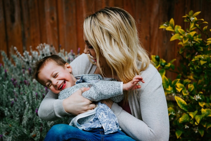 woman cuddling child and laughing