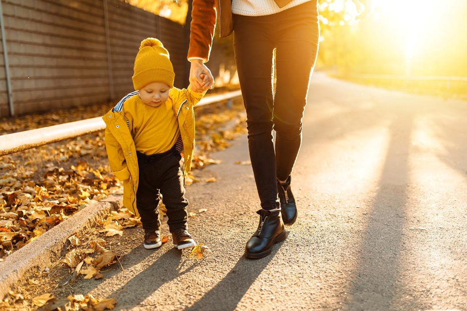 Mother and toddler walking together in autumn sunlight